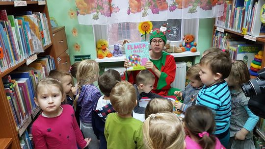 Przedszkolaki oprowadzane po bibliotece przez elfa