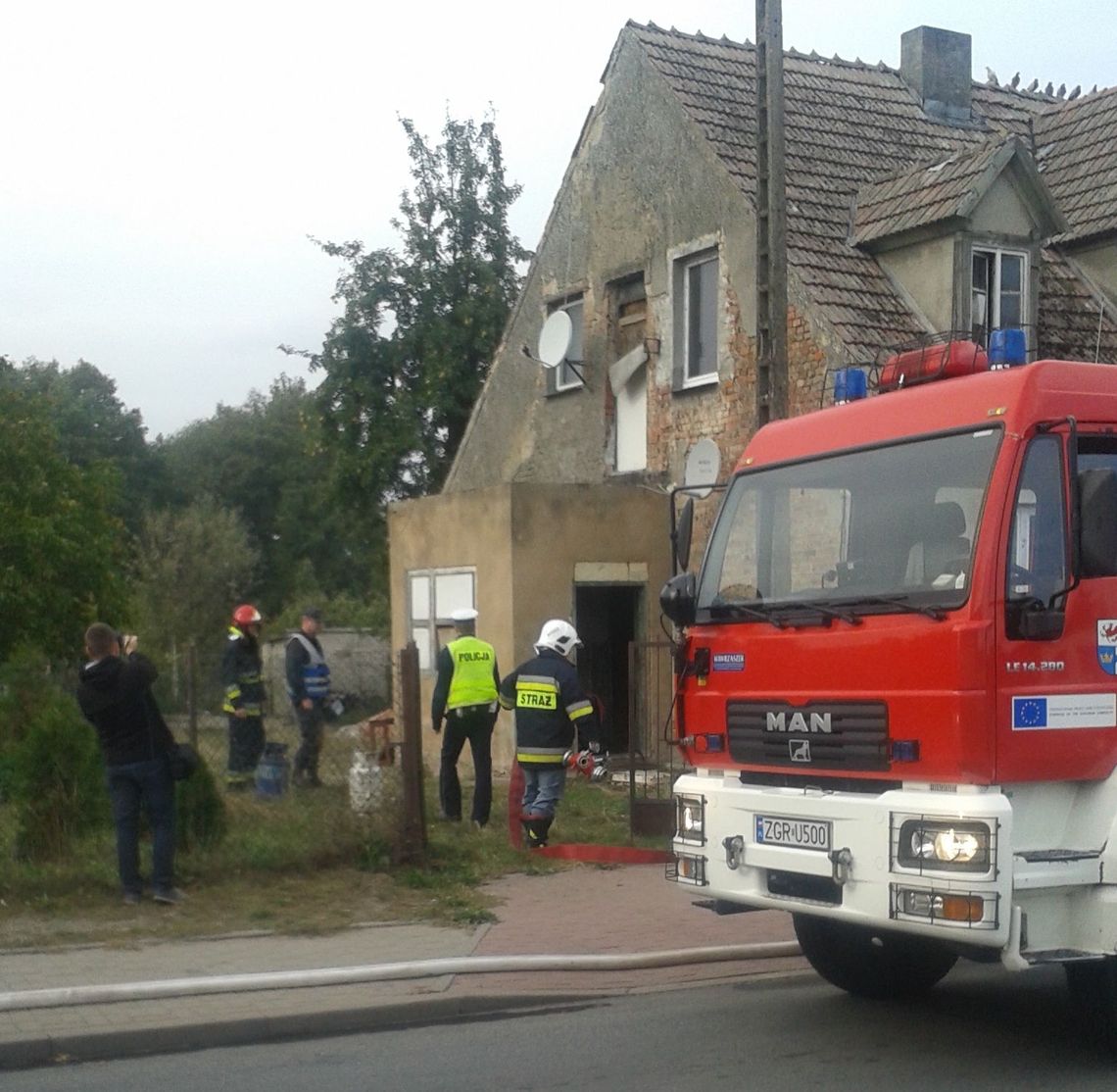 Wynoszą butlę z gazem z płonącego domu Wynoszą butlę z gazem z płonącego domu